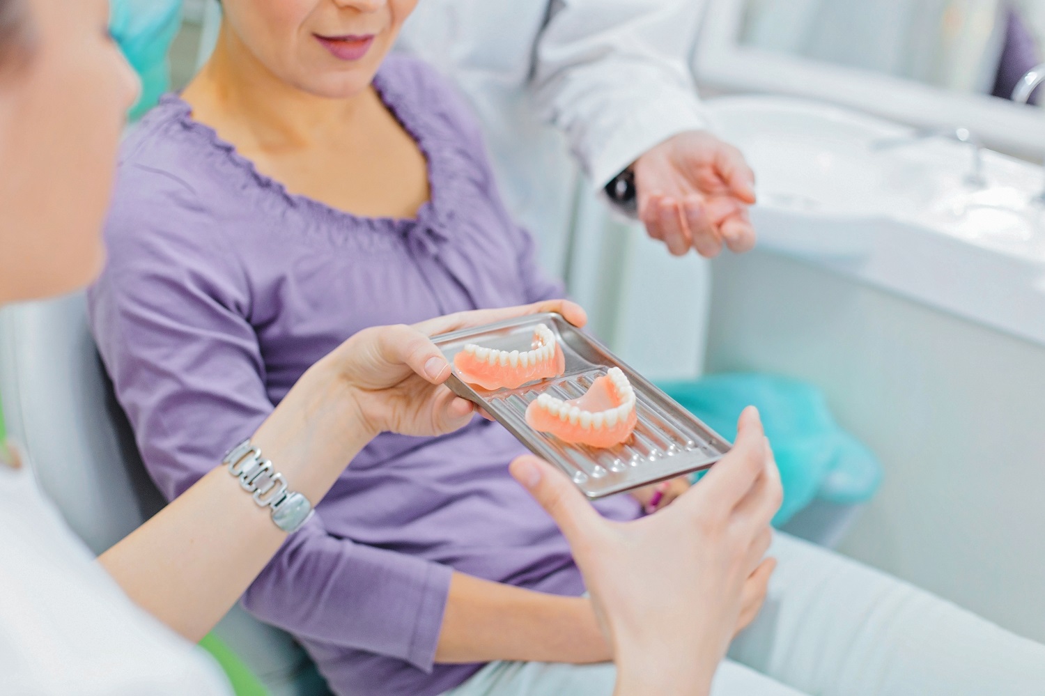 Dentist showing teeth dentures to a female patient